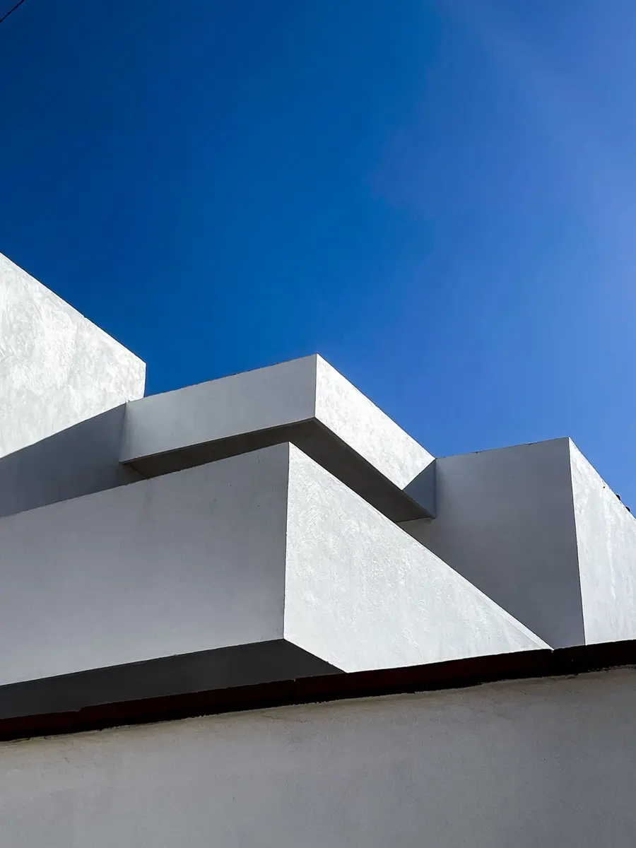 Detalle arquitectónico moderno en concreto blanco, formas angulares contra un cielo azul intenso